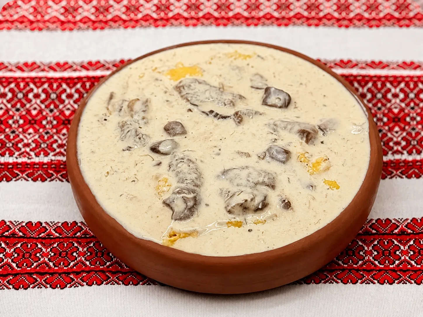 Банош із лісовими грибами у глиняній мисці