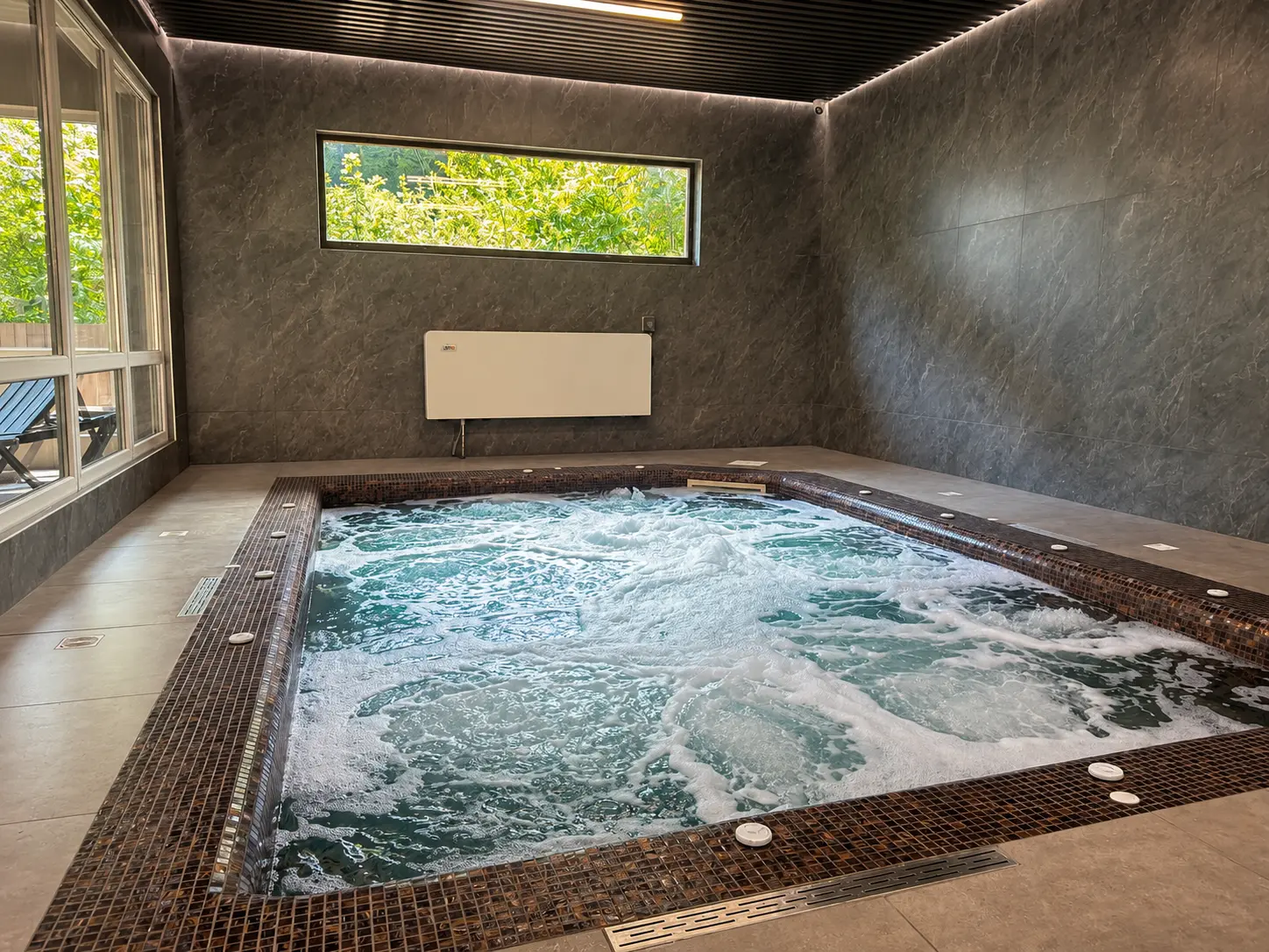 Джакузі SPA-комплексу: вода кипить під форсунками, панорамне вікно в сад