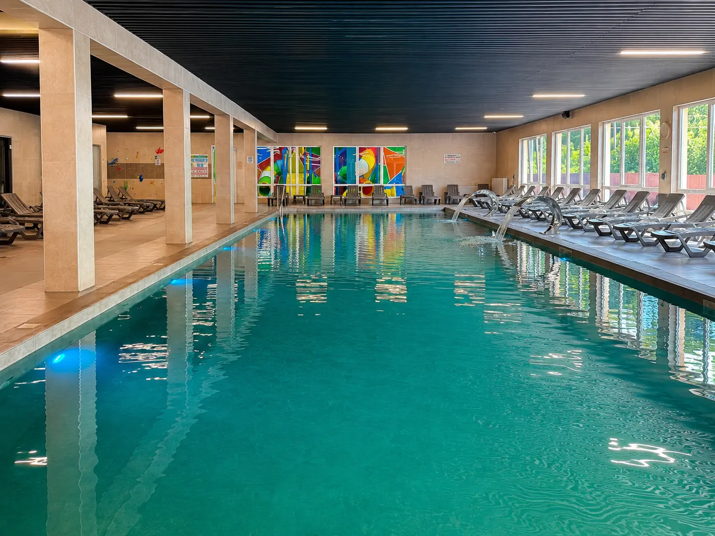 Великий критий басейн SPA-комплексу: бірюзова вода, шезлонги вздовж борту й водоспади